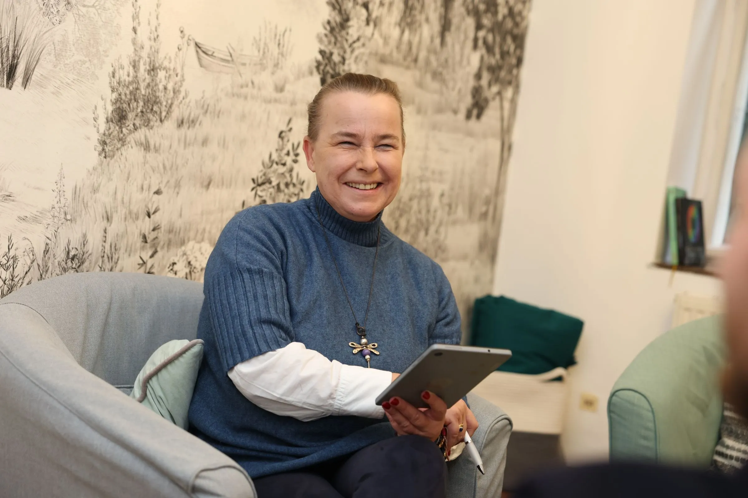Verena Broschek-Fellner im Gespräch, mit Tablet im Sessel
