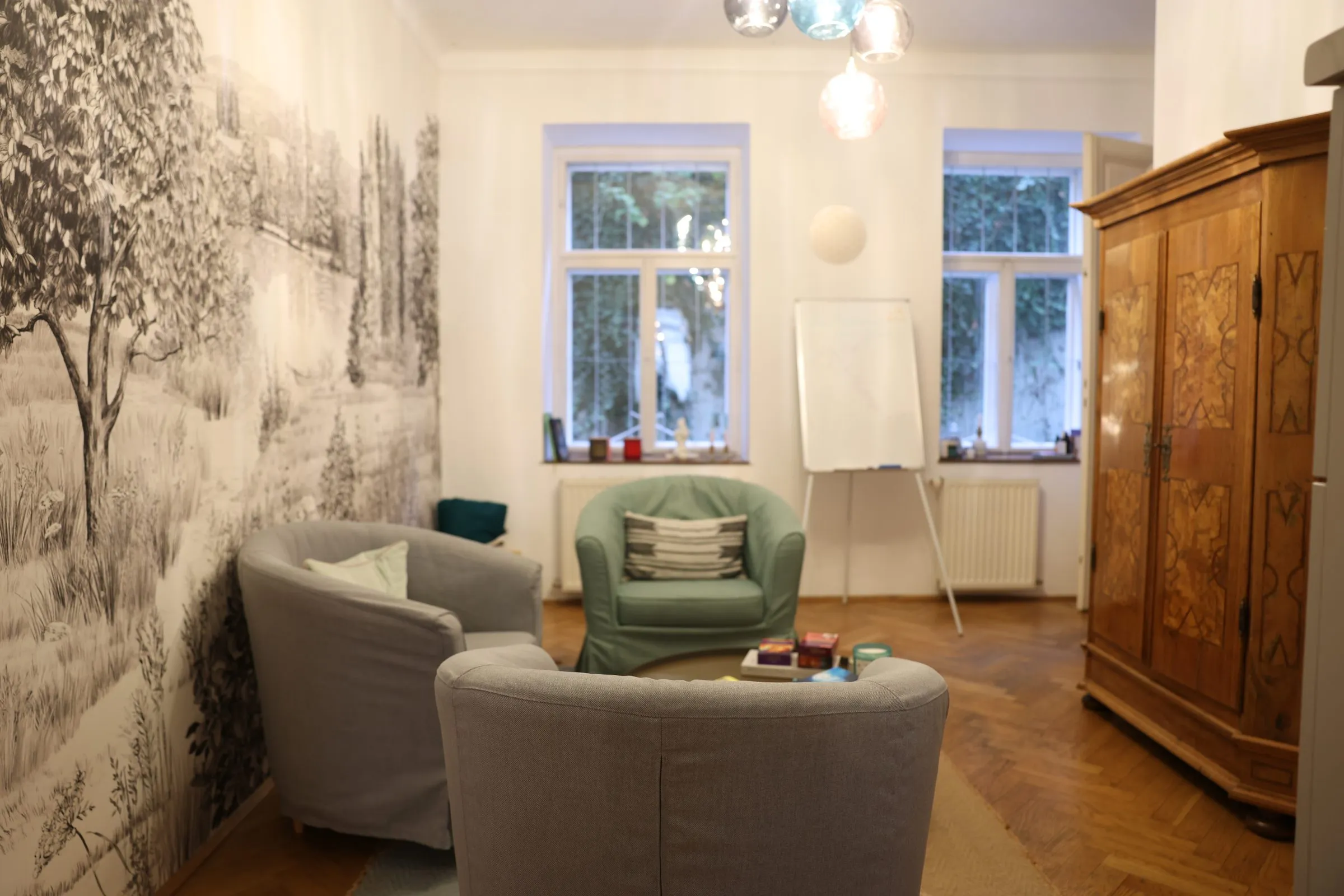Sessel, Flipchart und alter Holzschrank im Glücksraum