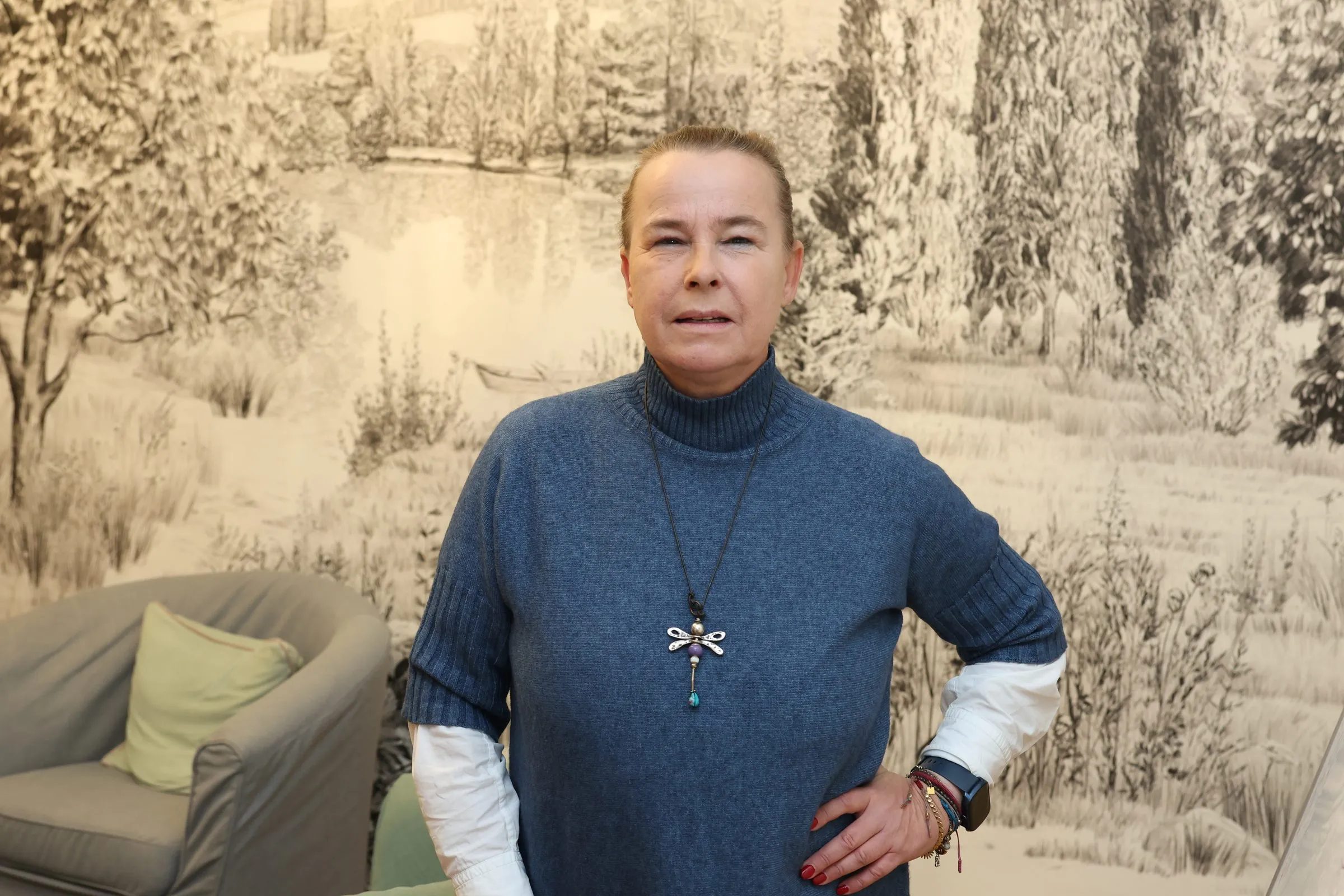 Verena Broschek-Fellner steht vor der gezeichneten Landschaftstapete im Glücksraum